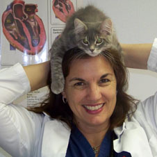 A woman in white lab coat holding up a cat.